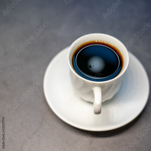 Close up of hot americano in white cup looking, and feel so delicious on gray table background.