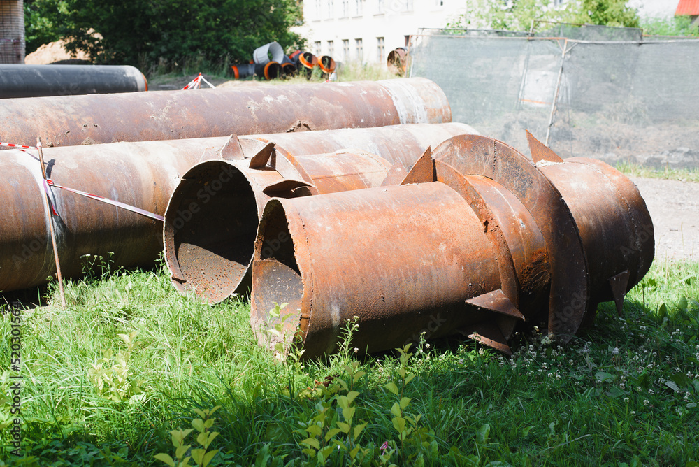 Worn rusty iron old pipes lying on ground outdoors, side view. City water supply repair, pipe replacement Worn rusty iron old pipes lying on ground outdoors, side view. City water supply repair, pipe replacement