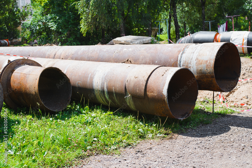 City water supply repair, pipe replacement. Old, worn out, rusty iron pipes lying on ground outdoors City water supply repair, pipe replacement. Old, worn out, rusty iron pipes lying on ground outdoors