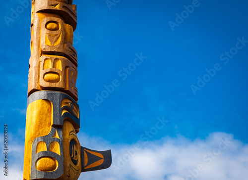 Isolated totem wood pole in blue sky background. Indian totem poles in park in Nanaimo, Canada photo