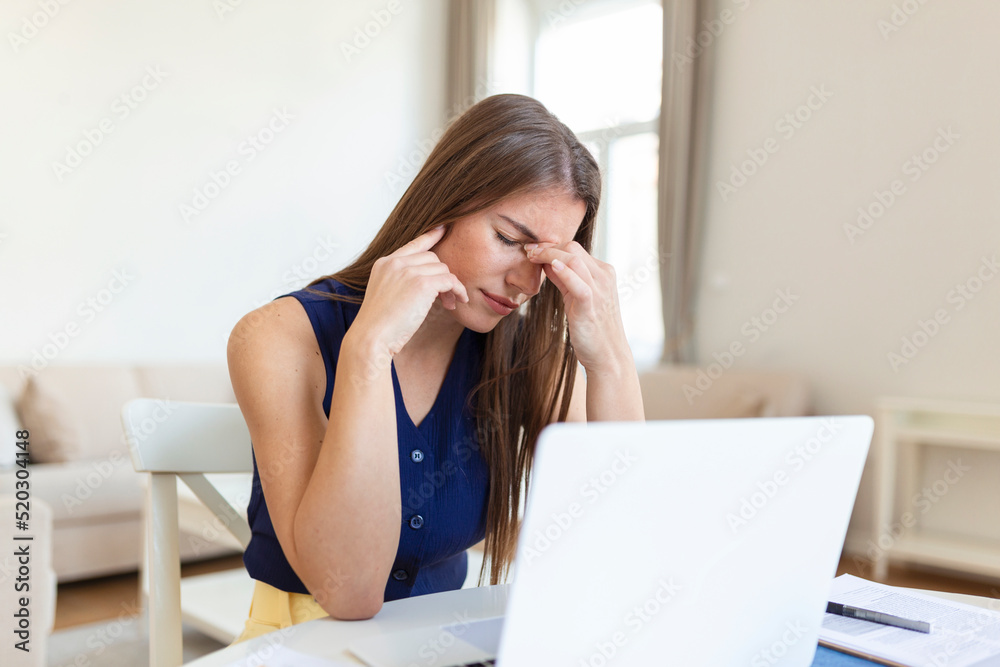 Young frustrated woman working at office desk in front of laptop suffering from chronic daily headaches, Young frustrated woman working at office desk in front of laptop suffering from chronic daily headaches,