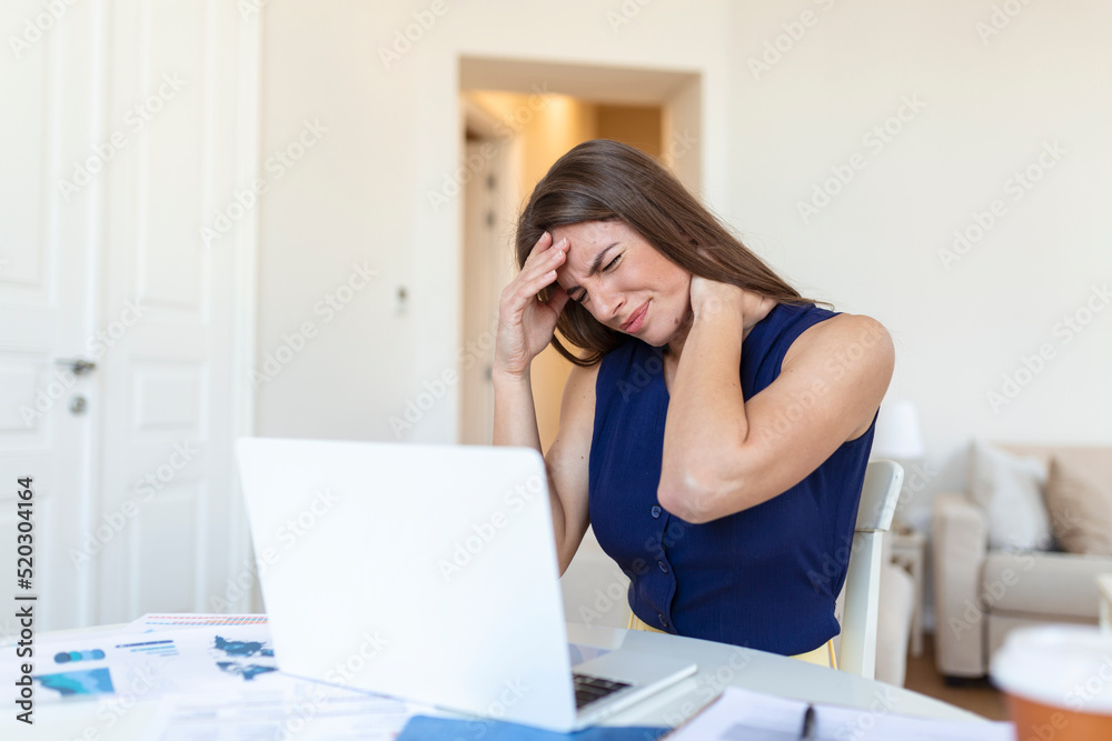 Young frustrated woman working at office desk in front of laptop suffering from chronic daily headaches, Young frustrated woman working at office desk in front of laptop suffering from chronic daily headaches,