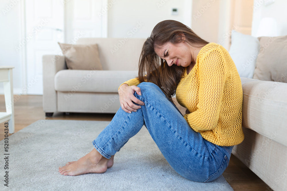 Woman lying on sofa looking sick in the living room. Beautiful young woman lying on bed and holding hands on her stomach. Woman having painful stomachache on bed, Menstrual period Woman lying on sofa looking sick in the living room. Beautiful young woman lying on bed and holding hands on her stomach. Woman having painful stomachache on bed, Menstrual period