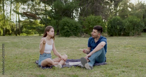 Young couple sit on a picnic in the woods and eat sushi with bamboo chopsticks and talk on green background photo