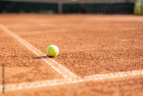 Bright greenish yellow tennis ball on the line.