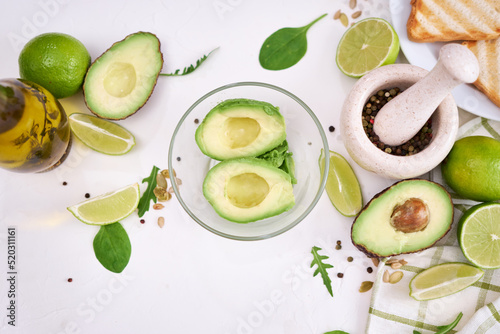 Making avocado toast - fresh ripe halved avocado in glass bowl and ingredients