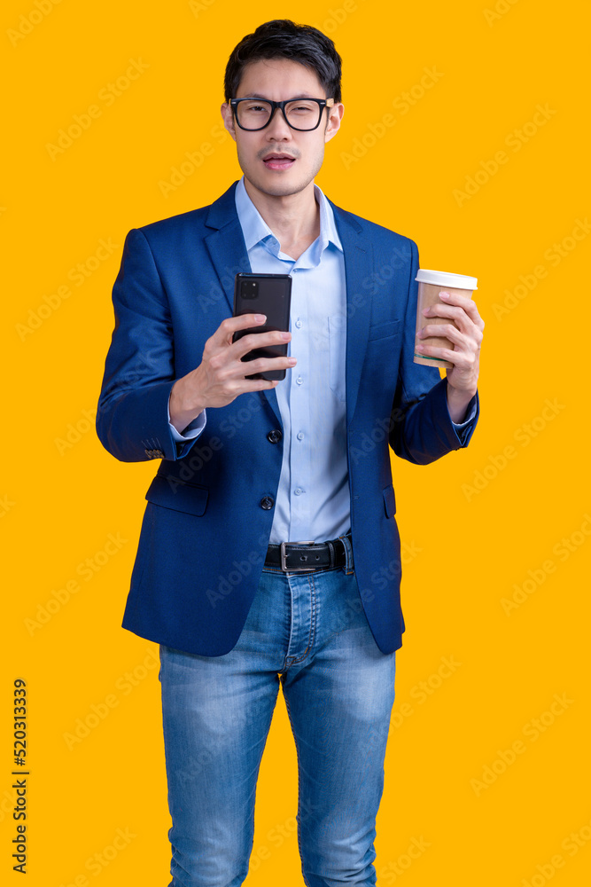 smart casual business asian male blue suit hand surfing internet leisure after work another hand hold coffee drink cup cheerful enjoy carefree moment isolate yellow background studio shot smart casual business asian male blue suit hand surfing internet leisure after work another hand hold coffee drink cup cheerful enjoy carefree moment isolate yellow background studio shot