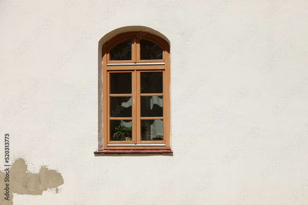 One brown arched window on white old wall with copy space