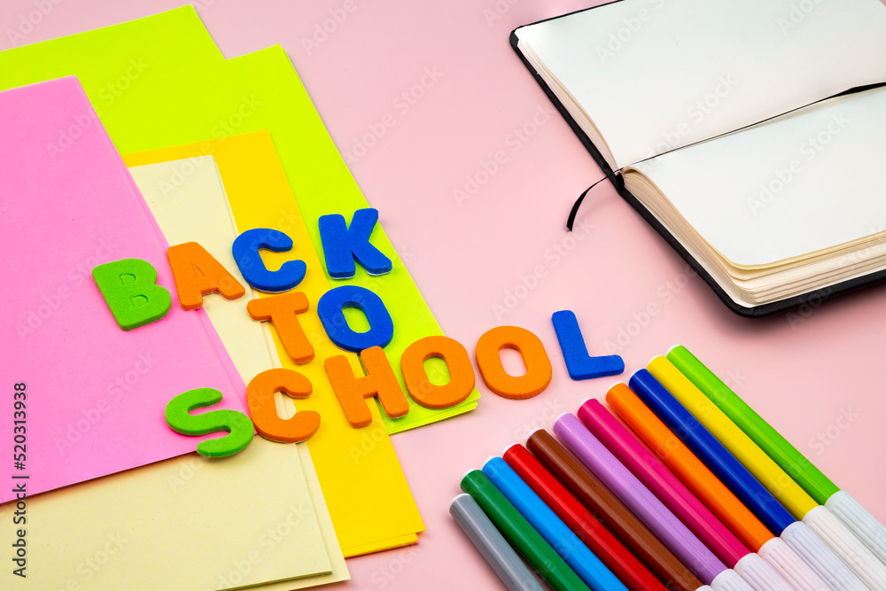 Back to school letters, with school supplies on top of a pink table.
