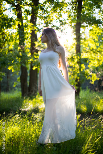 Wallpaper Mural Beautiful young Russian girl dressed in a white dress, walks through the forest among the oaks in the rays of the sunset Torontodigital.ca