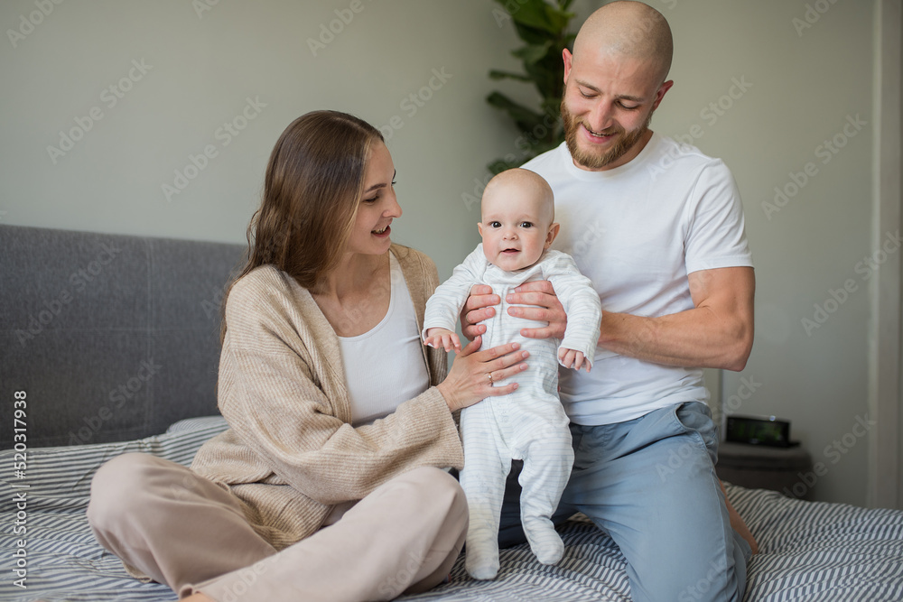 Happy family. Portrait of caucasian smiling mother father and newborn baby hugging at home. Motherhood. Loving parents mom and dad enjoy taking care of a little child. healthy child care Happy family. Portrait of caucasian smiling mother father and newborn baby hugging at home. Motherhood. Loving parents mom and dad enjoy taking care of a little child. healthy child care