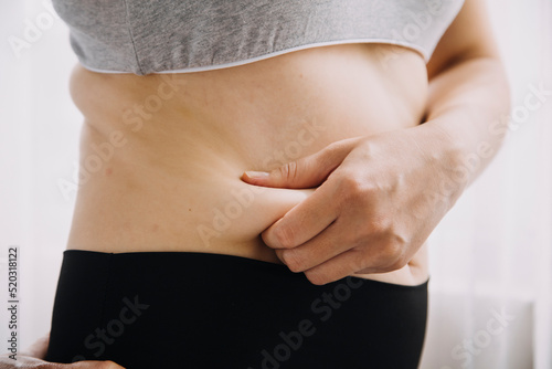 Beautiful fat woman with tape measure She uses her hand to squeeze the excess fat that is isolated on a white background. She wants to lose weight, the concept of surgery and break down fat under the