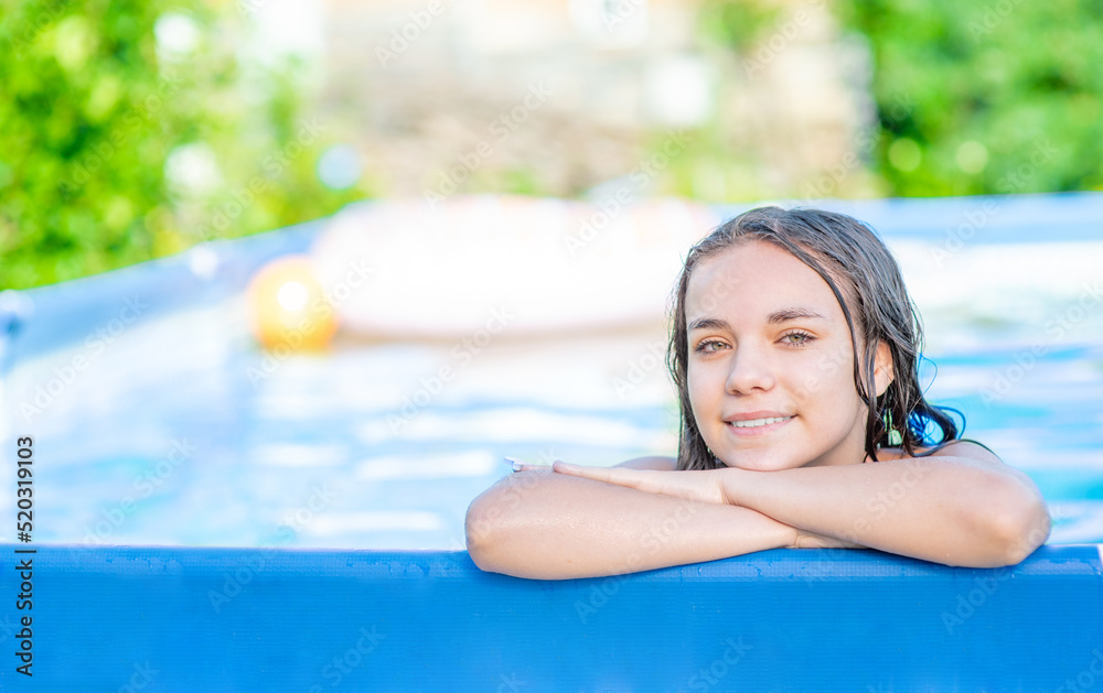 Happy teen girl enjoing in the pool at sunny day. Empty space for text