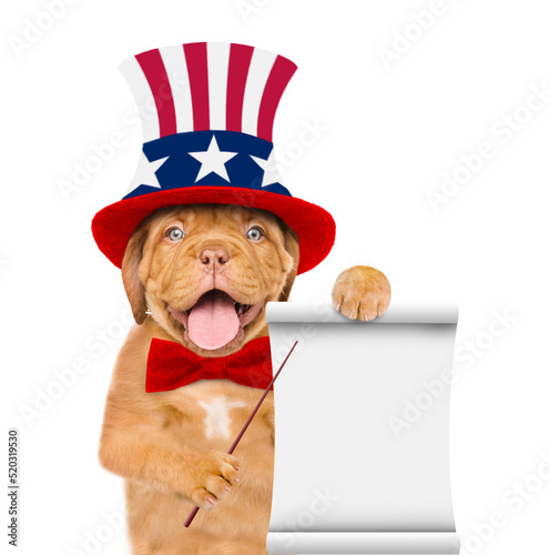 Happy Mastiff puppy wearing like Uncle Sam with sunglasses points on empty list. isolated on white background © Ermolaev Alexandr