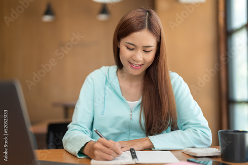 College education concept, Teenage girl watching video tutorial of tutor on laptop and taking notes