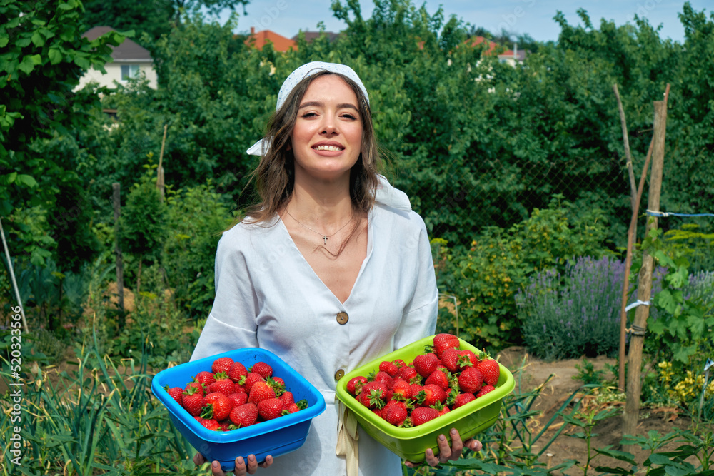 Young woman holding a harvest of strawberries in her hands