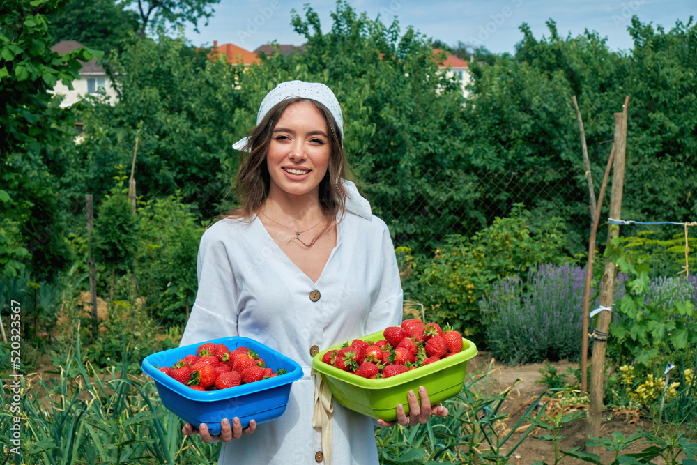 Young woman holding a harvest of strawberries in her hands