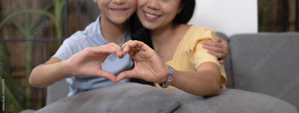 Asian mother and daughter making heart with their hands and smiling to camera. Life insurance, love and support in family relationships concept