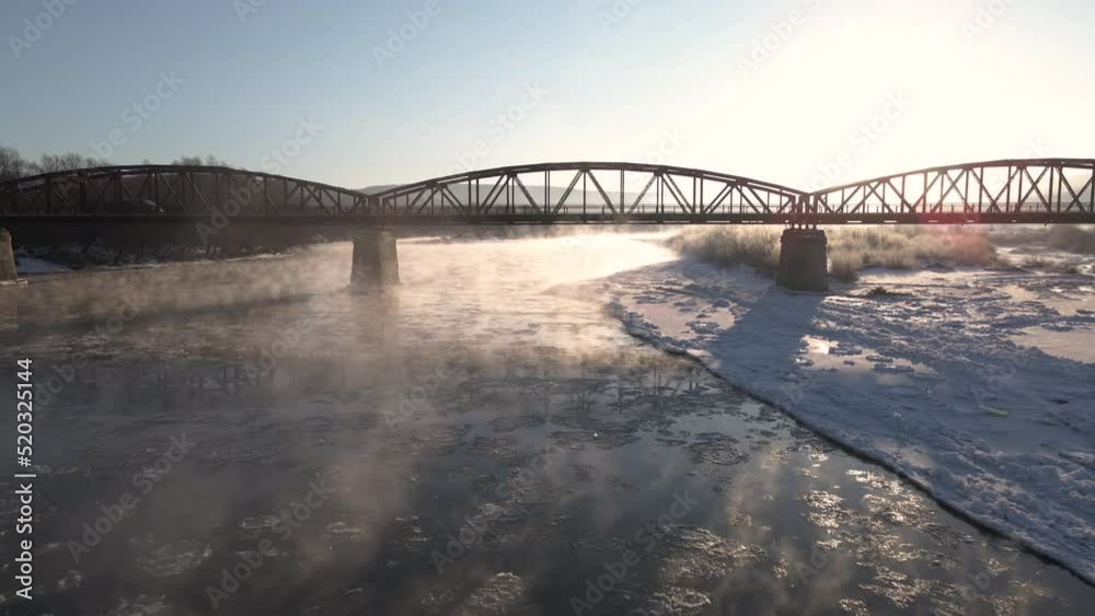 Drone Shot, Flies Backward Over the Frozen River at Sunrise, Car Driving on the Red Steel Bridge, Aerial 4k Footage Drone Shot, Flies Backward Over the Frozen River at Sunrise, Car Driving on the Red Steel Bridge, Aerial 4k Footage