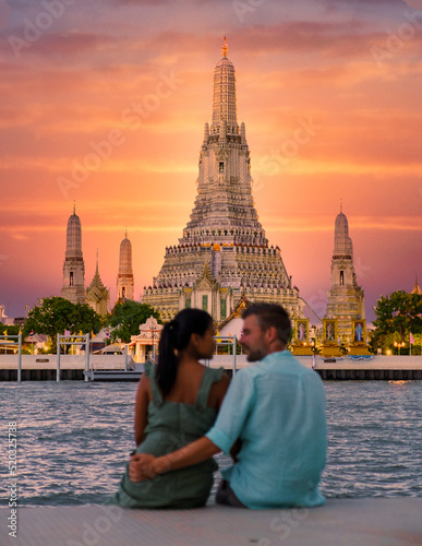 Photography Out of focus blur couple of Asian women and European men watching the sunset at Wat Arun temple in Bangkok Thailand, Temple of Dawn, Buddhist temple alongside the Chao Phraya River