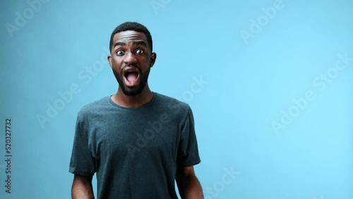 African american man taking off sunglasses surprised and saying wow looking at camera on blue background