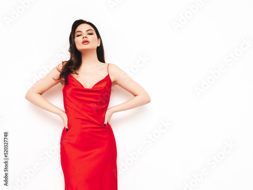 High fashion portrait of young beautiful brunette woman wearing nice trendy red evening dress. Sexy fashion model posing in studio. Fashionable female isolated on white © halayalex