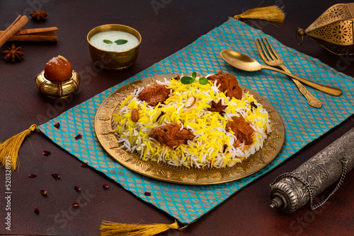 Indian spisy food Murgh Tikka Biryani or Chicken Tikka Biryani with raita and gulab jamun Served in a dish side view ramdan food on grey background photo