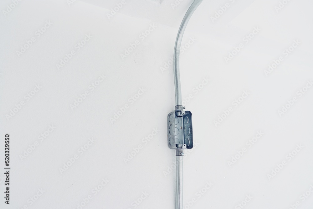 electric steel box and pipe on white concrete background. Electricity cable pipe line with box, the brilliant invention of modern electrical technology electric steel box and pipe on white concrete background. Electricity cable pipe line with box, the brilliant invention of modern electrical technology