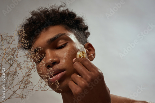 Black guy applying ice slice with plant on face