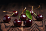 Sweet cherries with cherry leaf on a wooden background.