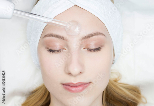 A beautiful young woman receiving a darsonval electric massage procedure in a beauty salon. Hardware cosmetology. Selective focus. photo
