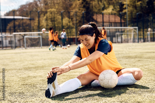 Female player stretching while warming up for soccer match on stadium. © Drazen
