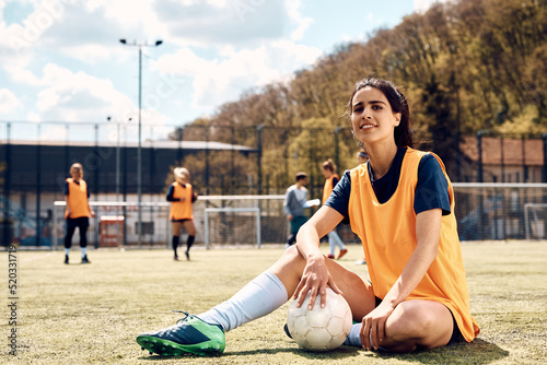 Fototapeta Naklejka Na Ścianę i Meble -  Female soccer player with ball on playing field looking at camera.