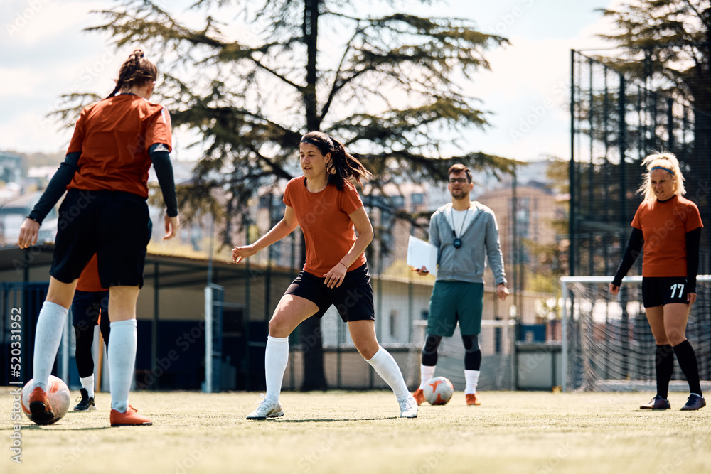 Female soccer players in action on football pitch.