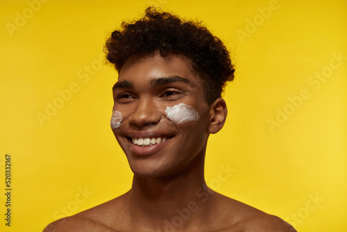 Smiling black guy with cream on his face look away