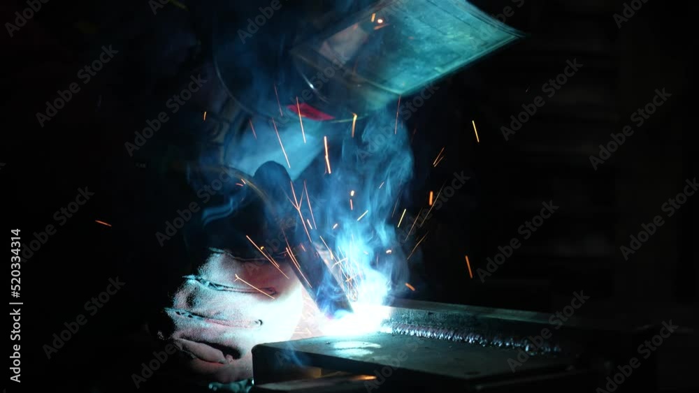Welder at work close-up, bright sparks in the dark Welder at work close-up, bright sparks in the dark