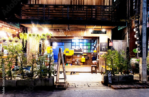 Fototapeta Naklejka Na Ścianę i Meble -  Chiangkhan, Loei/Thailand - DECEMBER 14, 2019: Local coffee shop decorated with beautiful light and old woody on the street road at night time, the small coffee shop, coffee cafe'. Pictured at night.