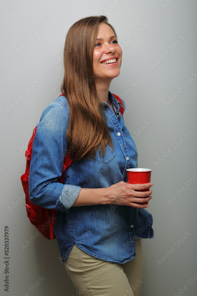 Smiling female student isolated portrait with red coffee glass looking side away. Smiling female student isolated portrait with red coffee glass looking side away.