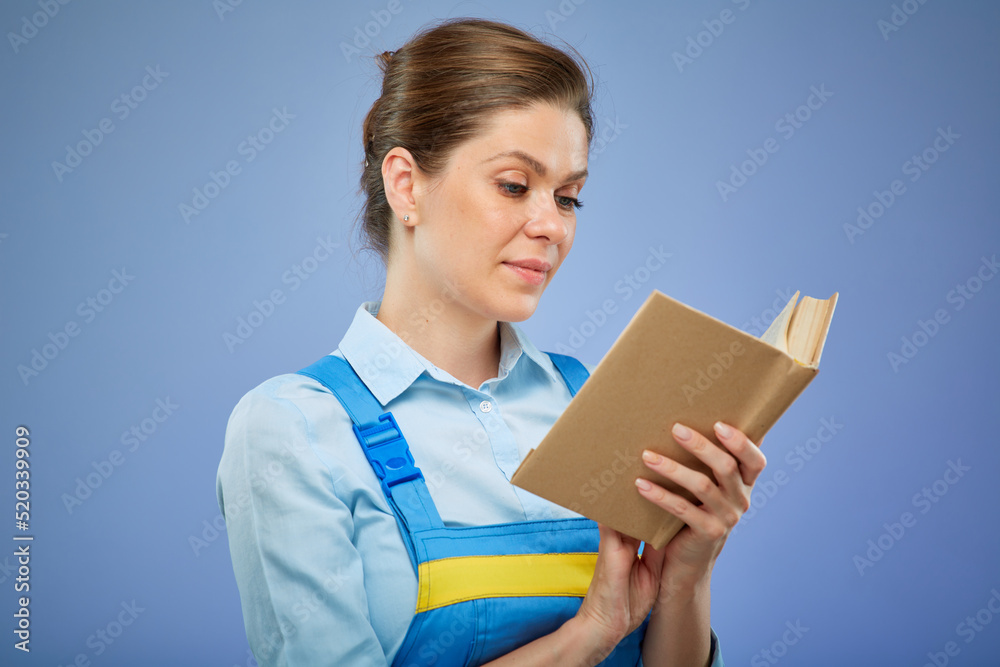 woman in blue overalls reading open book. Isolated female portrait. vocational school concept. woman in blue overalls reading open book. Isolated female portrait. vocational school concept.