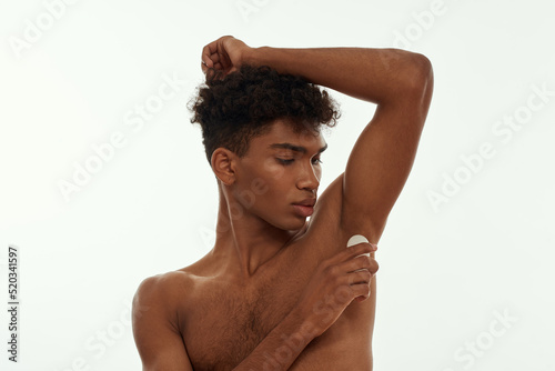 Black guy apply antiperspirant deodorant on armpit