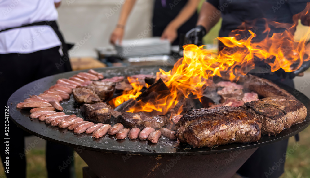Grilling meat and sausages on a round barbecue with an open fire. Peknik Grilling meat and sausages on a round barbecue with an open fire. Peknik