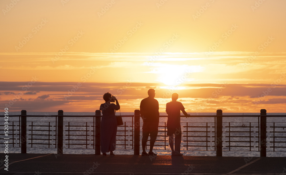 People watching the sunset by the sea in the city of Donostia-San Sebastian, Basque Country.