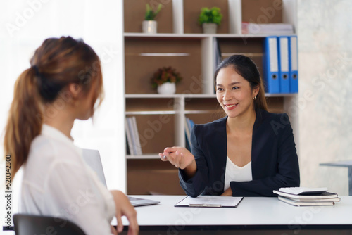 Two young Asian businesswomen discuss the concept of a new start-up project. Analyze marketing planning and financial statement at the office.