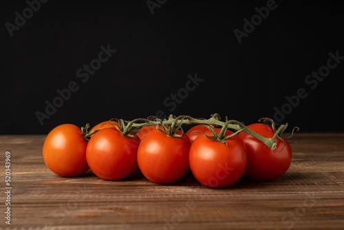 Red ripe tomatoes lie on an oak table.