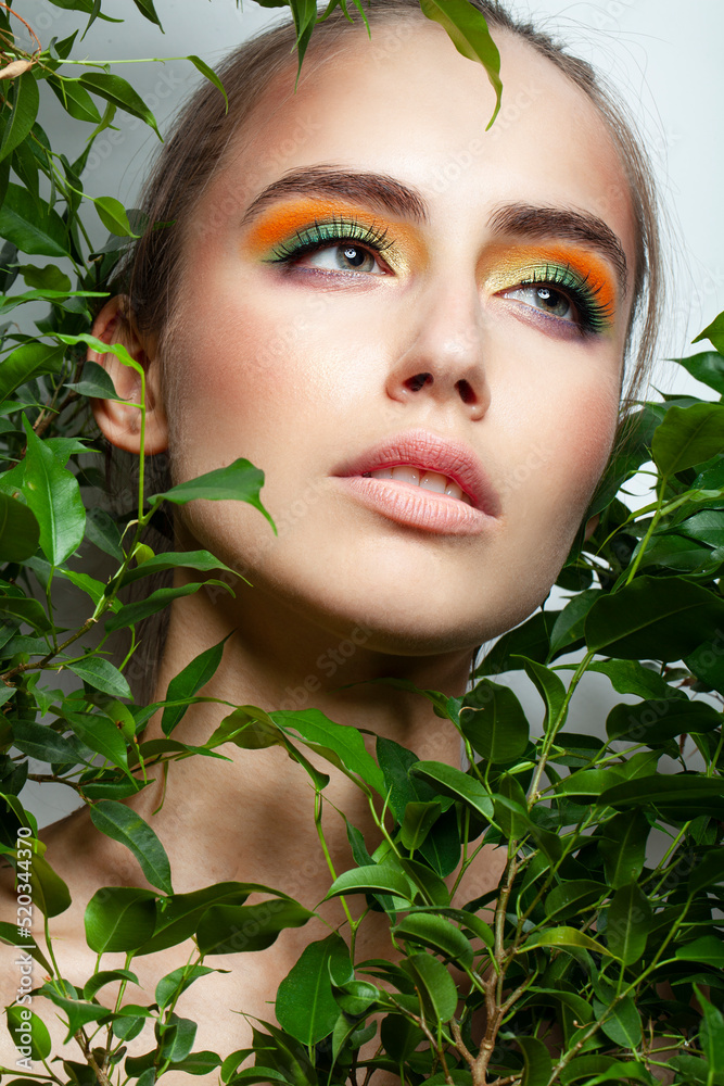 Closeup face of an attractive caucasian girl with makeup posing near green plants. Closeup face of an attractive caucasian girl with makeup posing near green plants.