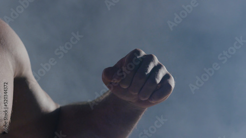 The man in boxing gloves. Young Boxer fighter over black background. Boxing man ready to fight. Strength training and boxing. Close-up of hand of boxer ready for a fight.