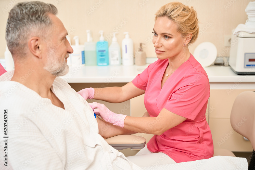 Obraz premium Nurse puts a tourniquet on his shoulder before taking blood