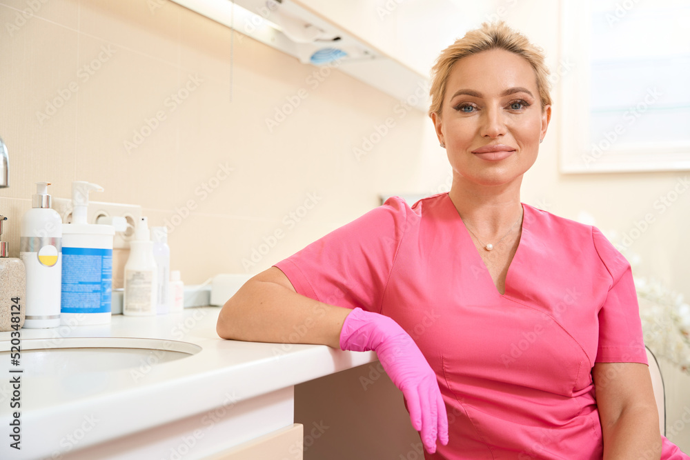 Smiling woman beautician sitting in chair leaning on table Smiling woman beautician sitting in chair leaning on table