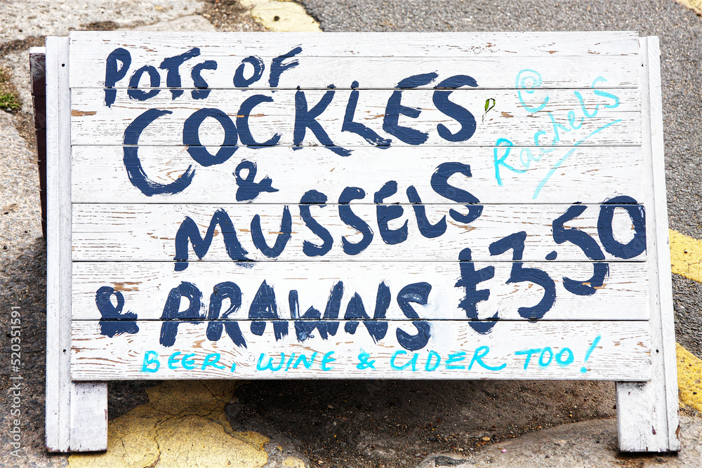Fototapeta premium Sign advertising cockles mussels and prawns seafood at british seaside