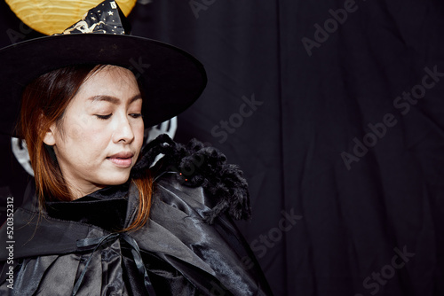 Asian young witch Halloween woman portrait and black spider on shoulder close up with copy space. Sorcerer makeup with Fashion art design as attractive model in Halloween costume on black background
